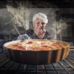 Blick aus dem Herd, dampfende Speise, Frau schaut freudig